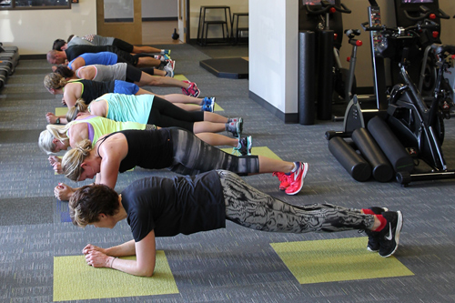 gym members perform plank pose
