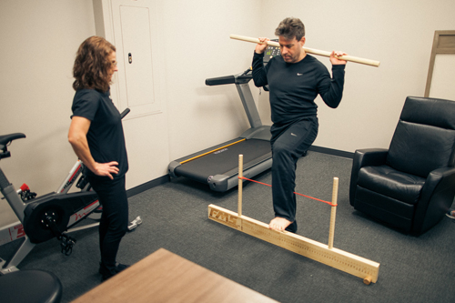 Physical Therapist monitors member's standing exercise