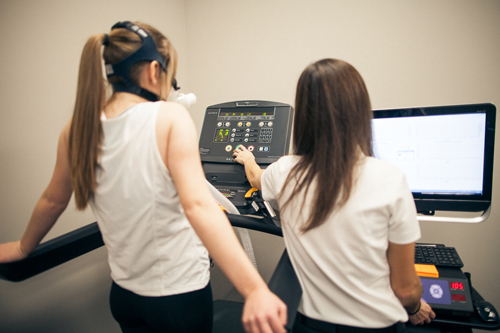female personal trainer assists female member with treadmill