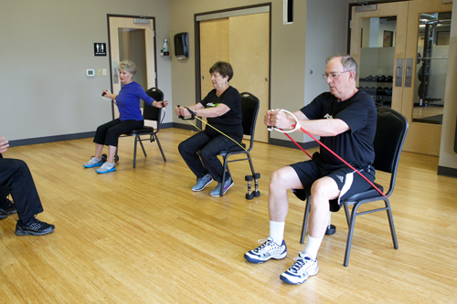 members of senior fit class perform seated shoulder raises