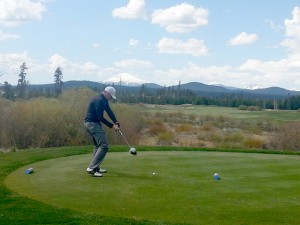 male golfer on green swinging club