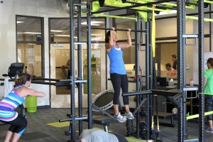 female doing pull-up on bar in health club
