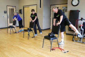 people perform standing side leg extension in gym room