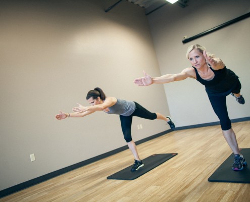 Two females performing standing one legged yoga pose