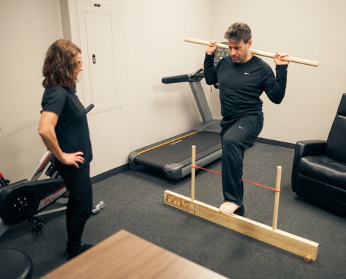 Physical Therapist monitors member's standing exercise