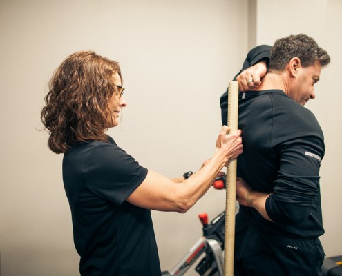 Physical Therapist measures range of motion on male with hands reaching behind back