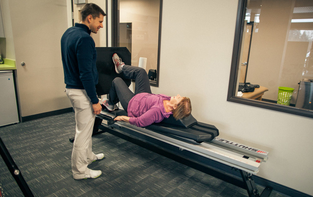 Physical therapist working with client on leg press machine
